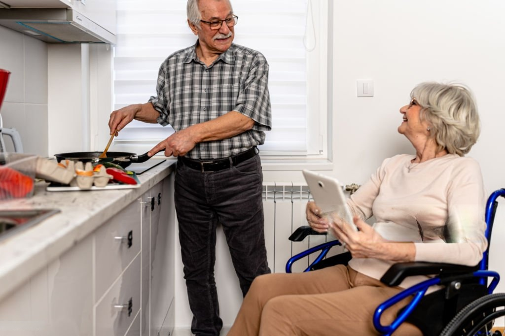 Senior couple cooking together at home, one using a wheelchair